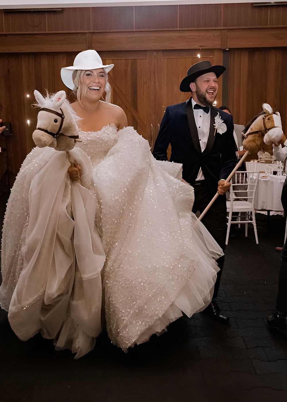 Couple making their entry into the wedding reception on stick horses